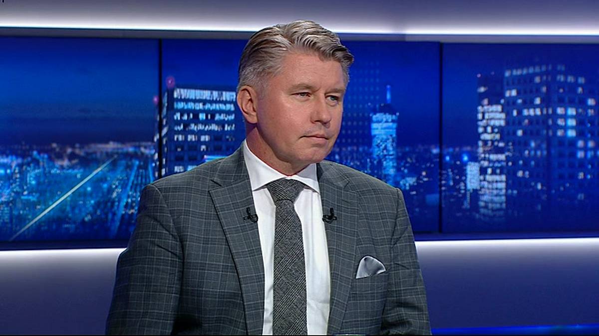 Mężczyzna w garniturze siedzi przed ekranem z widokiem nocnego miasta.