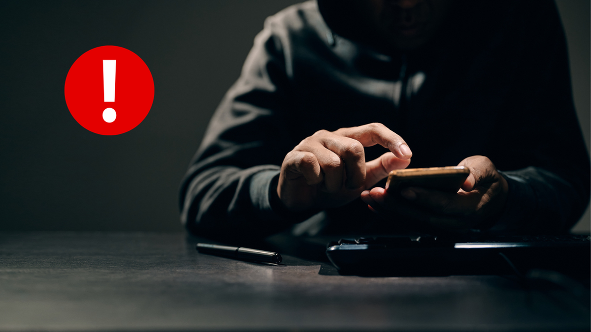 Osoba korzystająca z telefonu kom&oacute;rkowego z symbolem ostrzeżenia