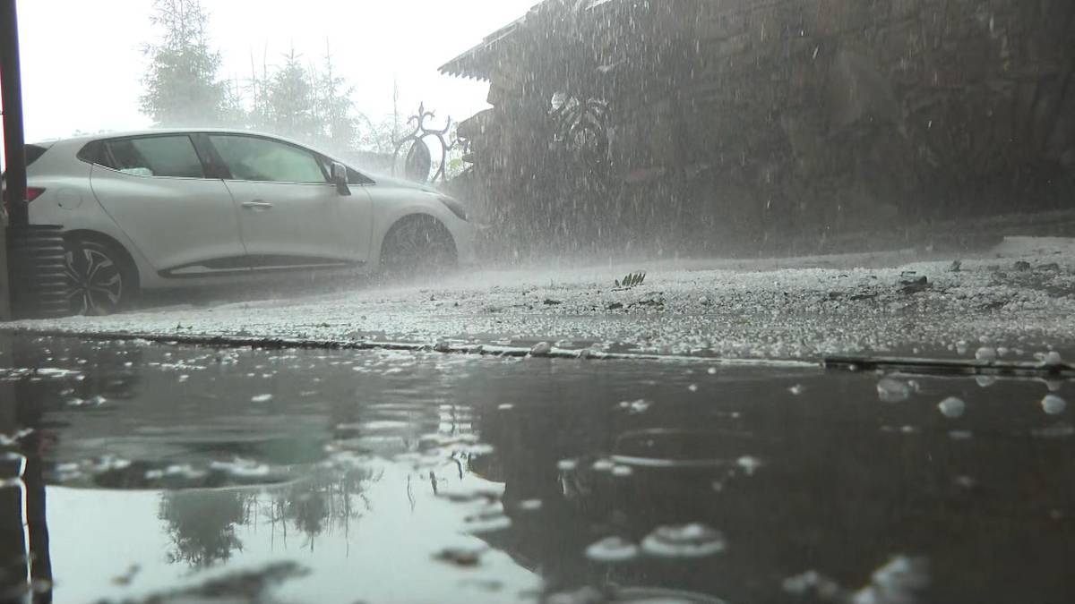 Samoch&oacute;d zaparkowany na zewnątrz podczas intensywnego deszczu i gradu.