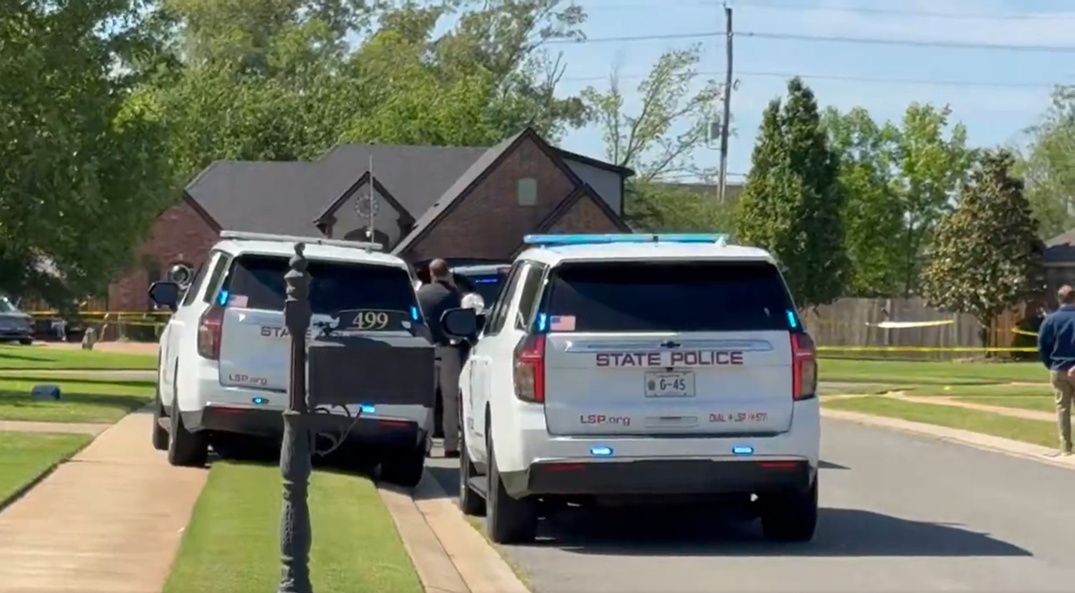 Radiowozy policyjne przy zabezpieczonym terenie przed domem.