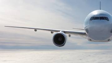 Fragment samolotu pasażerskiego w locie na tle nieba i chmur.