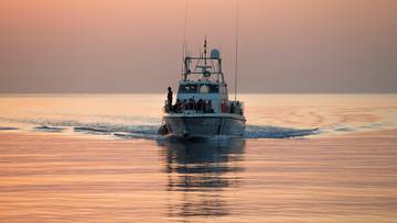 Ł&oacute;dź patrolowa na morzu o zachodzie słońca