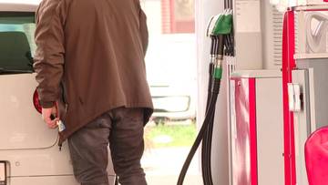 Osoba tankująca samoch&oacute;d na stacji benzynowej.