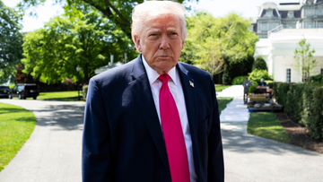 Donald Trump w garniturze z krawatem stoi na zewnątrz.